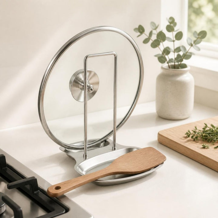 Lid rack holding a glass pot lid and wooden spatula on a white counter beside the stove