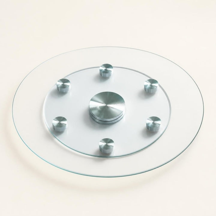 24 inch clear tempered glass lazy susan with center bearing and six support wheels on a warm ivory background