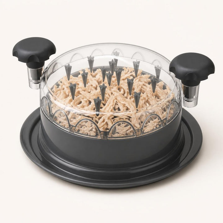Chicken shredder with clear spiked lid and black knob handles on a warm ivory background