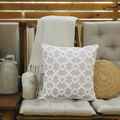 Beige geometric textured throw pillow on a cushioned bench with a knit throw