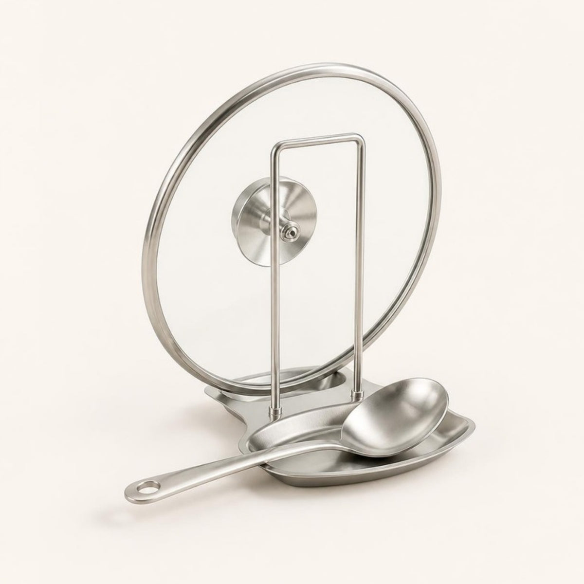 Stainless steel pot lid and spatula rack holding a glass lid and spoon, ivory background