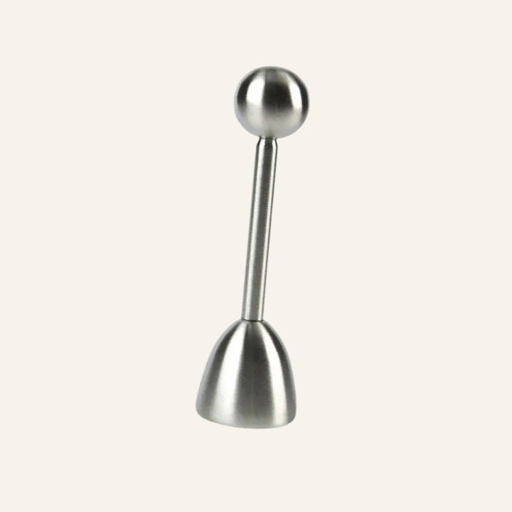 Stainless steel egg topper standing upright on an ivory background