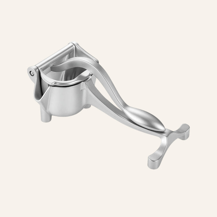 Aluminum lever press juicer on an ivory background