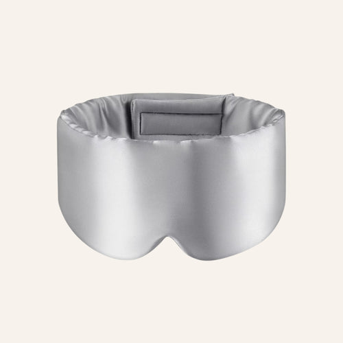 Light gray mulberry silk sleep mask on a warm ivory background