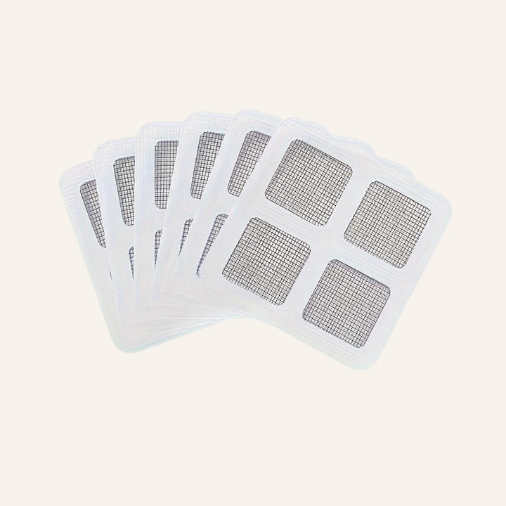 Fanned stack of square disposable drain hair catchers on a warm ivory background