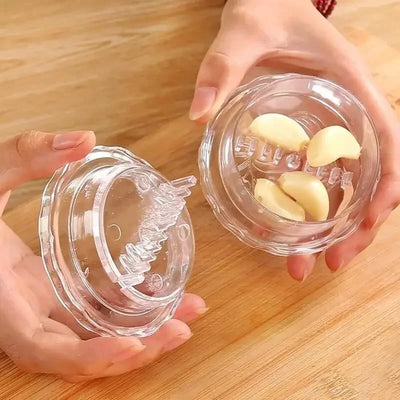 Hands holding the clear garlic crusher open with peeled garlic cloves inside