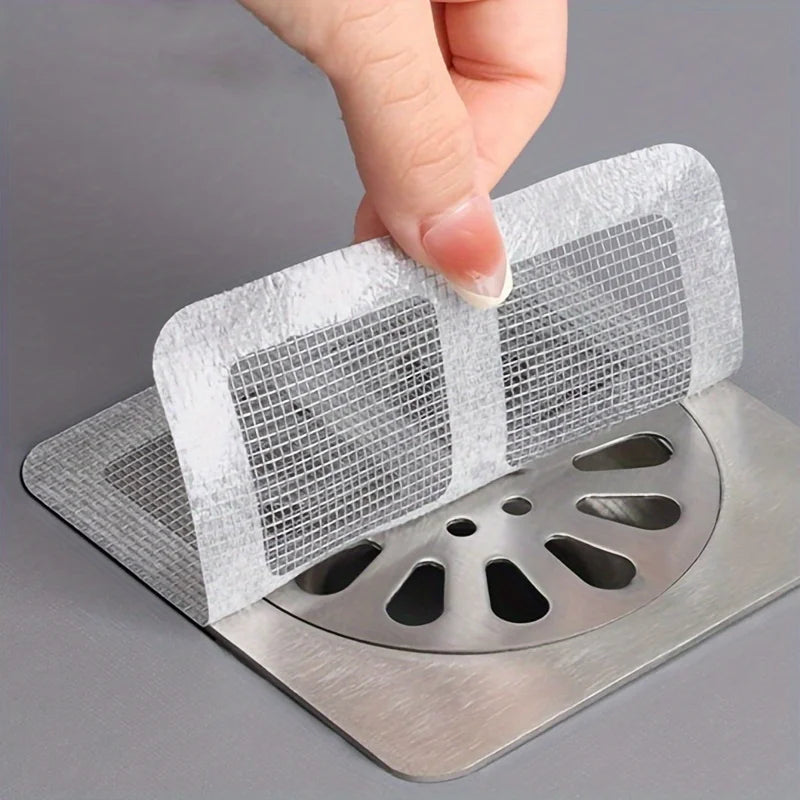 Hand applying a square mesh hair catcher over a floor drain