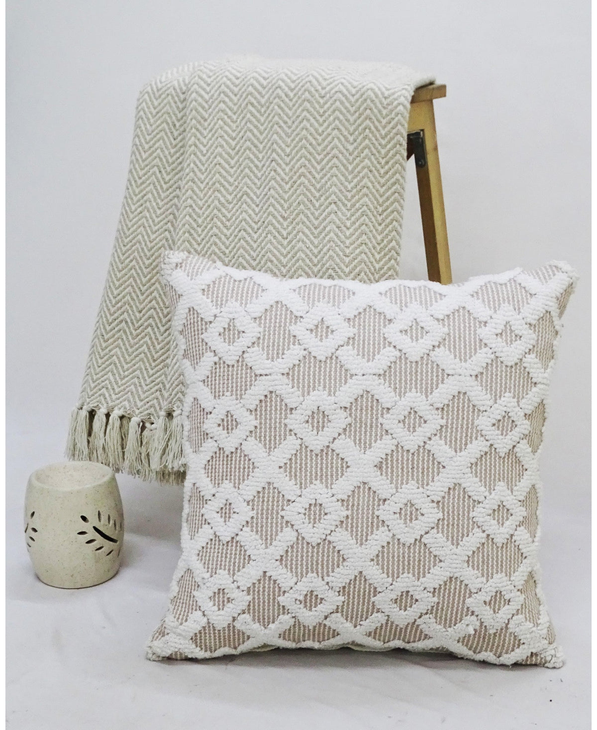 Beige and off-white geometric throw pillow with a knit throw and ceramic vase