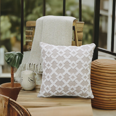 Beige geometric textured throw pillow styled on a wooden table on a patio