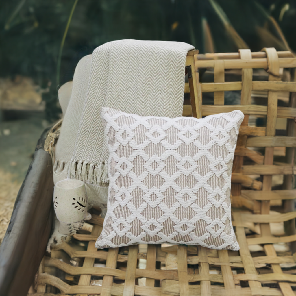 Beige geometric textured throw pillow with a cream knit throw on a woven wooden chair